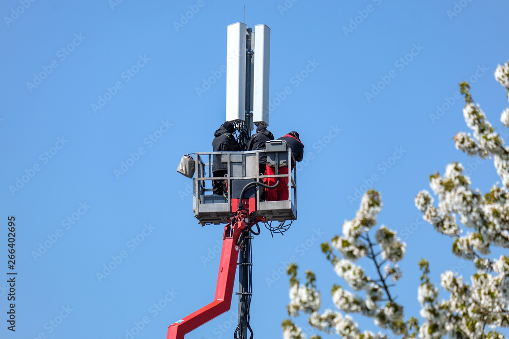 Fachleute auf einer Hebebühne arbeiten an einem Sendemast bei blauem Himmel – viel Copyspace Fachleute auf einer Hebebühne arbeiten an einem Sendemast bei blauem Himmel – viel Copyspace