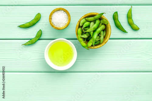 Green soybeans and oil background on mint green wooden desk top view