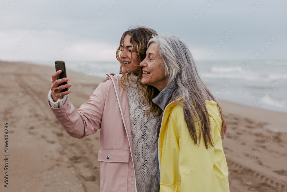 Senior woman and her daughter taking a selfie on the beach. Senior woman and her daughter taking a selfie on the beach.