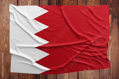 Flag of Bahrain on a wooden table background. Wrinkled Bahraini flag top view.