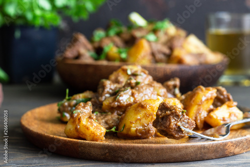 Meat stew with potatoes and parsley in wooden dish. Traditional Portuguese meat stew. Wooden background.