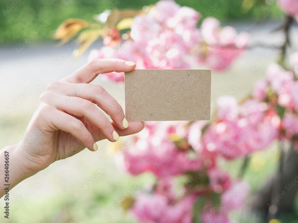Hand holding a craft business visit card, gift, ticket, pass, present close up on nature background Hand holding a craft business visit card, gift, ticket, pass, present close up on nature background