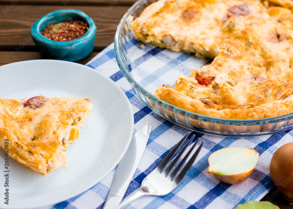Rustic large tart and piece with cloth on a wooden table, view from above, close-up
