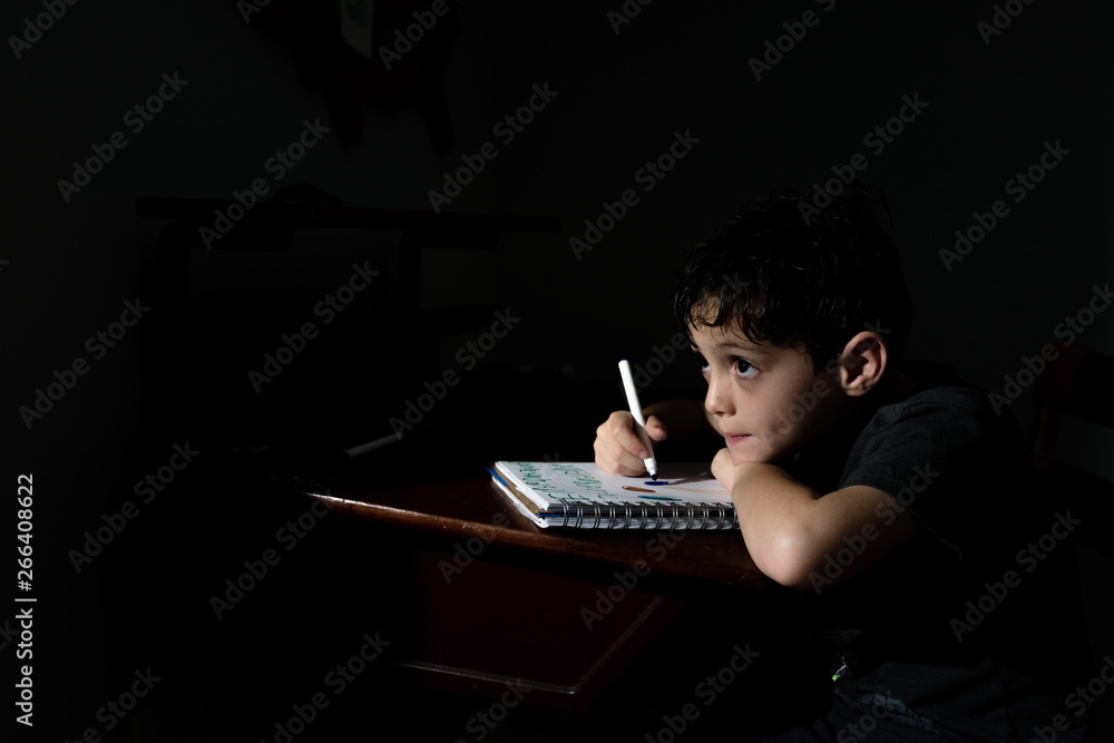 A Boy Writing In His Notebook At His Desk A Night A Boy Writing In His Notebook At His Desk A Night