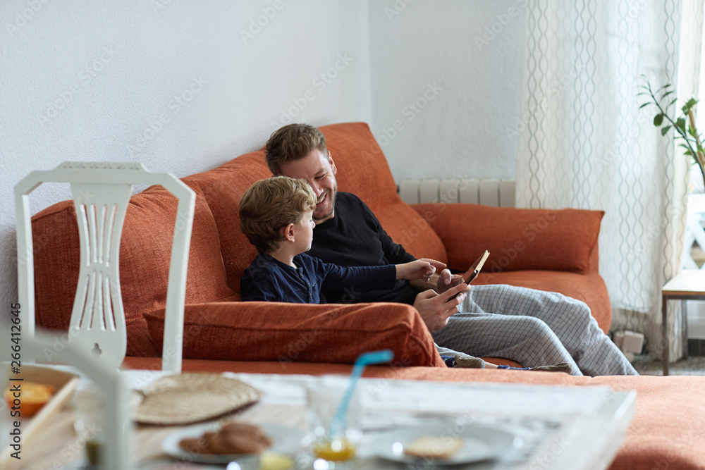 Dad and son playing together with a digital tablet at home Dad and son playing together with a digital tablet at home