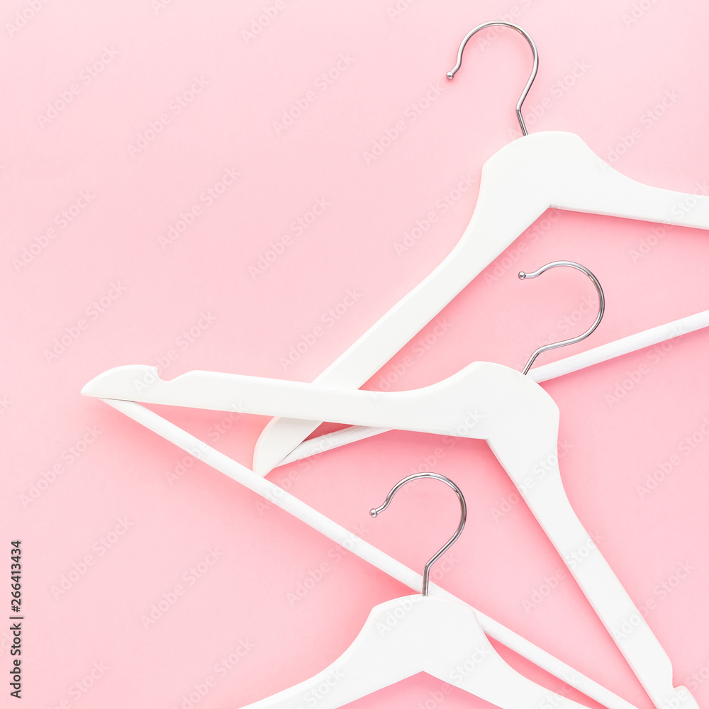 White hangers on pastel pink background White hangers on pastel pink background