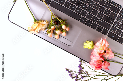 White table with laptop and flowers. Freelancer workspace.