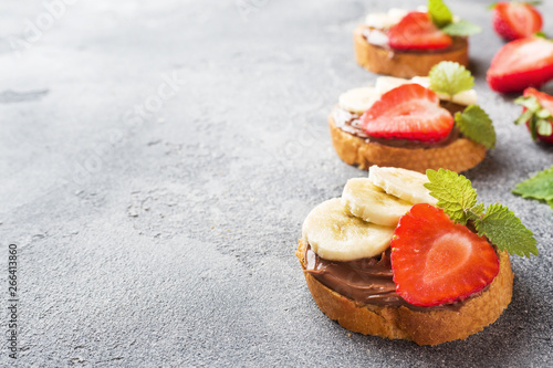 Delicious sandwiches with chocolate nougat, strawberry and banana. Concept of Breakfast. Dark concrete background Copy space