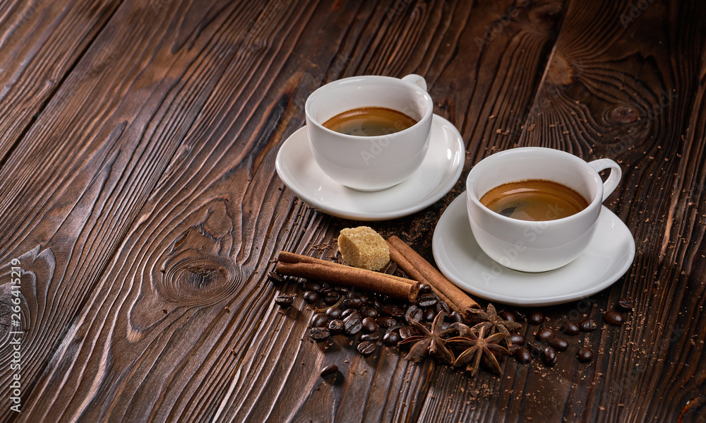 Two cups of freshly brewed espresso coffee with coffee beans on a rustic wooden table Two cups of freshly brewed espresso coffee with coffee beans on a rustic wooden table