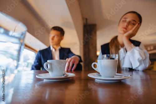 a stylish couple drinks morning coffee at the cafe, the girl is sleeping, the boy is looking out the window