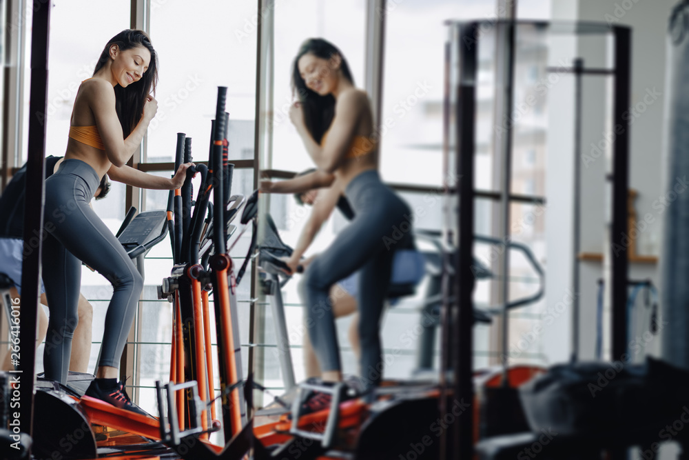 young attractive girl at gym on exercise bike, fitness and yoga young attractive girl at gym on exercise bike, fitness and yoga
