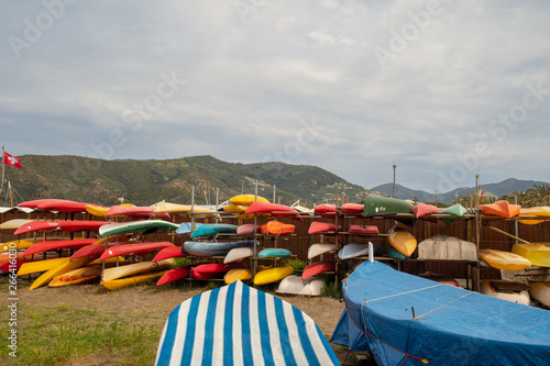 Scenic view of a storage of colorful kayaks  canoe and sup boards on the beach of the Bay of the Fairy Tales in Sestri Levante with covered rowing boats in the foreground in springtime  Liguria  Italy