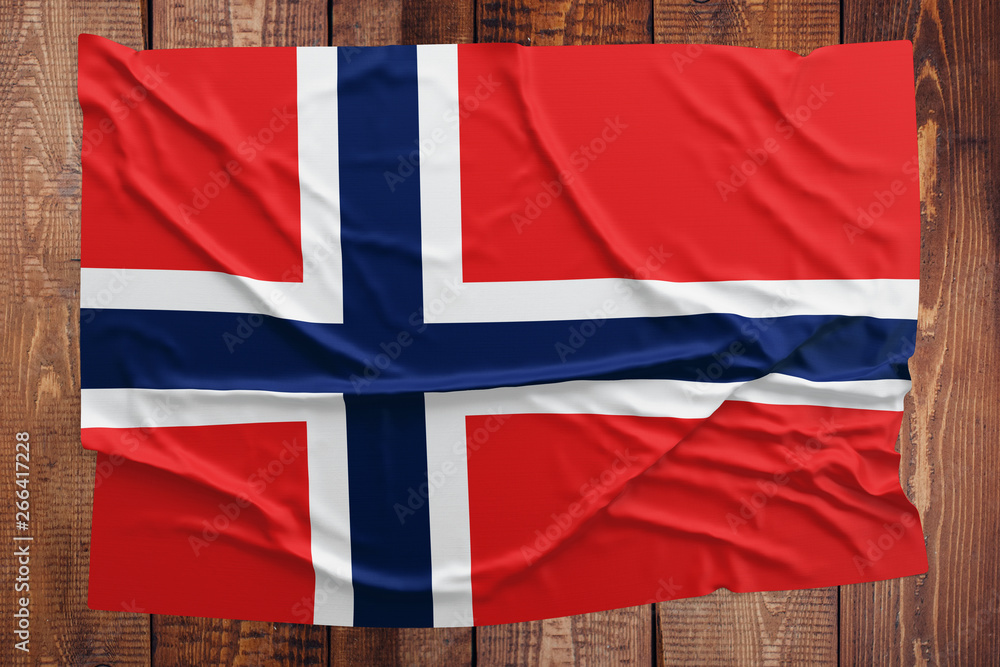 Flag of Norway on a wooden table background. Wrinkled Norwegian flag top view.