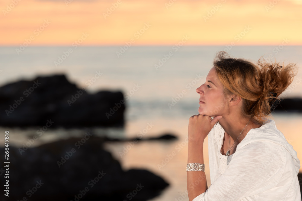 Beautiful young woman sitting at the wild coast of the swedish island Faroe, enjoying the summer evening. Beautiful young woman sitting at the wild coast of the swedish island Faroe, enjoying the summer evening.