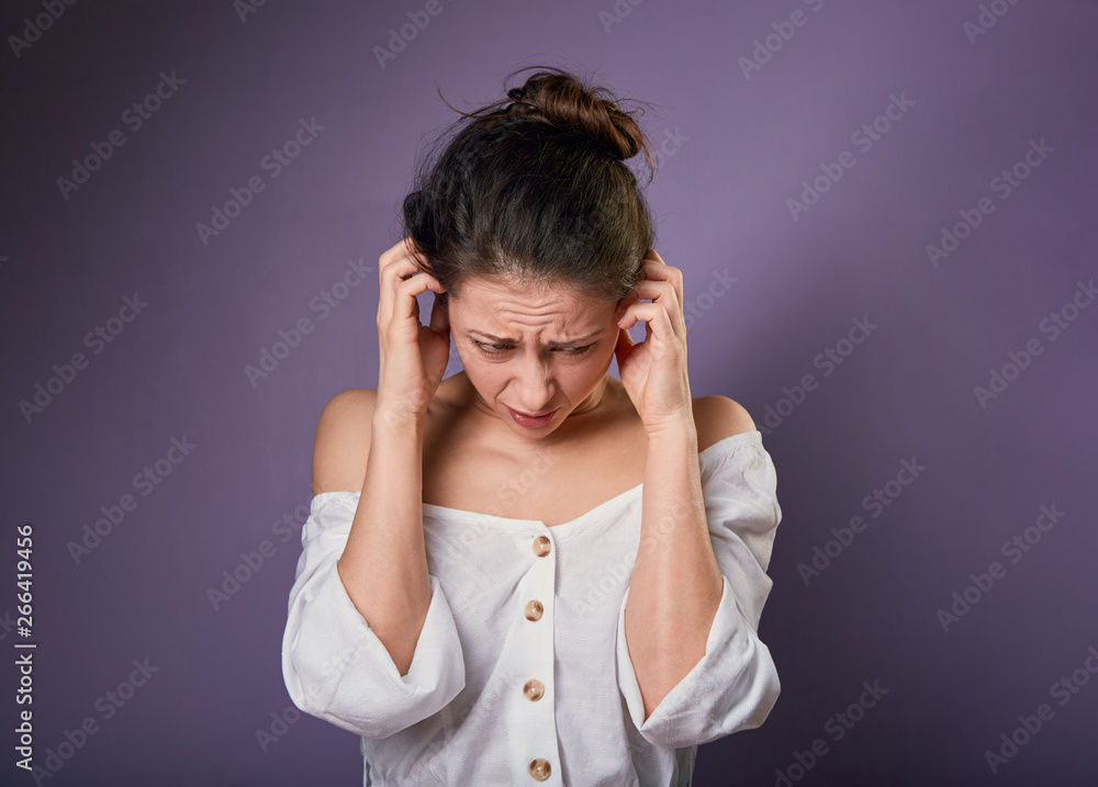 Stressed uncertain casual woman closed ears the fingers because not want the hear any sounds and noise on purple background. Closeup Stressed uncertain casual woman closed ears the fingers because not want the hear any sounds and noise on purple background. Closeup