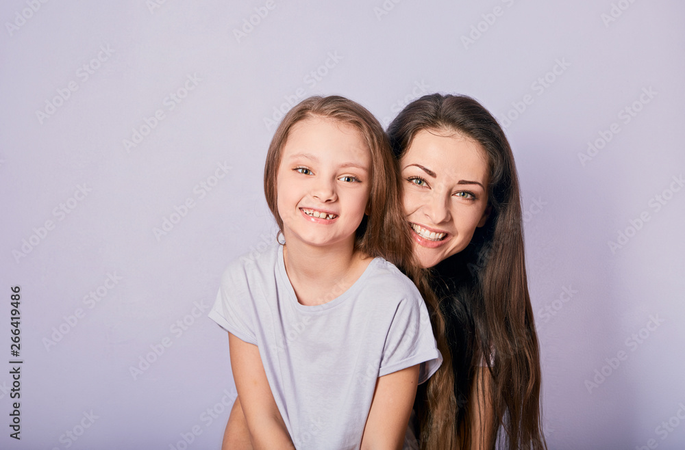 Mother and kid girl hugging with happy emotional toothy smiling faces on purple background with empty copy space. Closeup Mother and kid girl hugging with happy emotional toothy smiling faces on purple background with empty copy space. Closeup