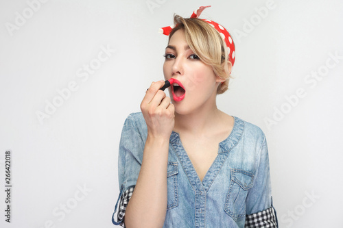 Wallpaper Mural Portrait of beautiful sexual beauty blogger young woman in casual blue denim shirt with makeup and red headband standing, applying red lipstick. Torontodigital.ca