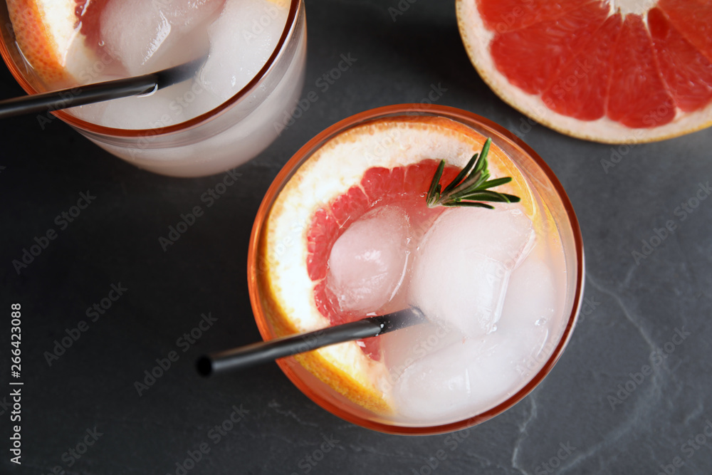 Glasses of cocktail and grapefruit slice on dark table, flat lay - obrazy, fototapety, plakaty 