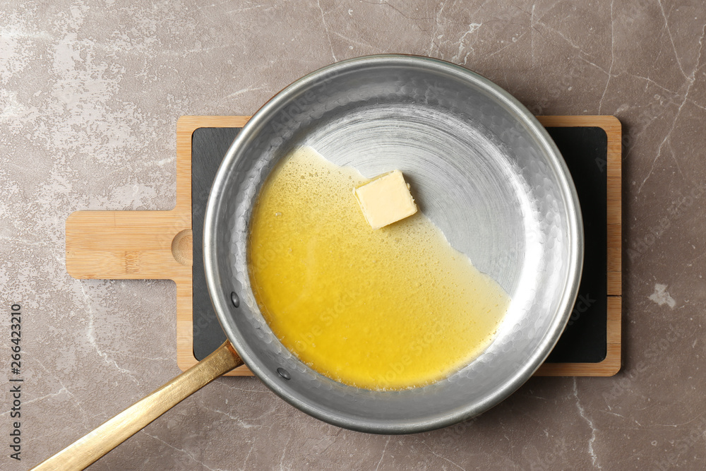 Frying pan with melting butter on grey background, top view Frying pan with melting butter on grey background, top view