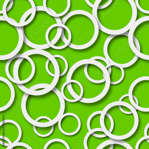 Abstract seamless pattern of randomly arranged white rings with soft shadows on green background