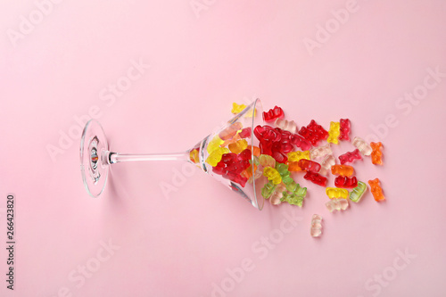 Φωτογραφία Martini glass with delicious color jelly bears on color background, top view