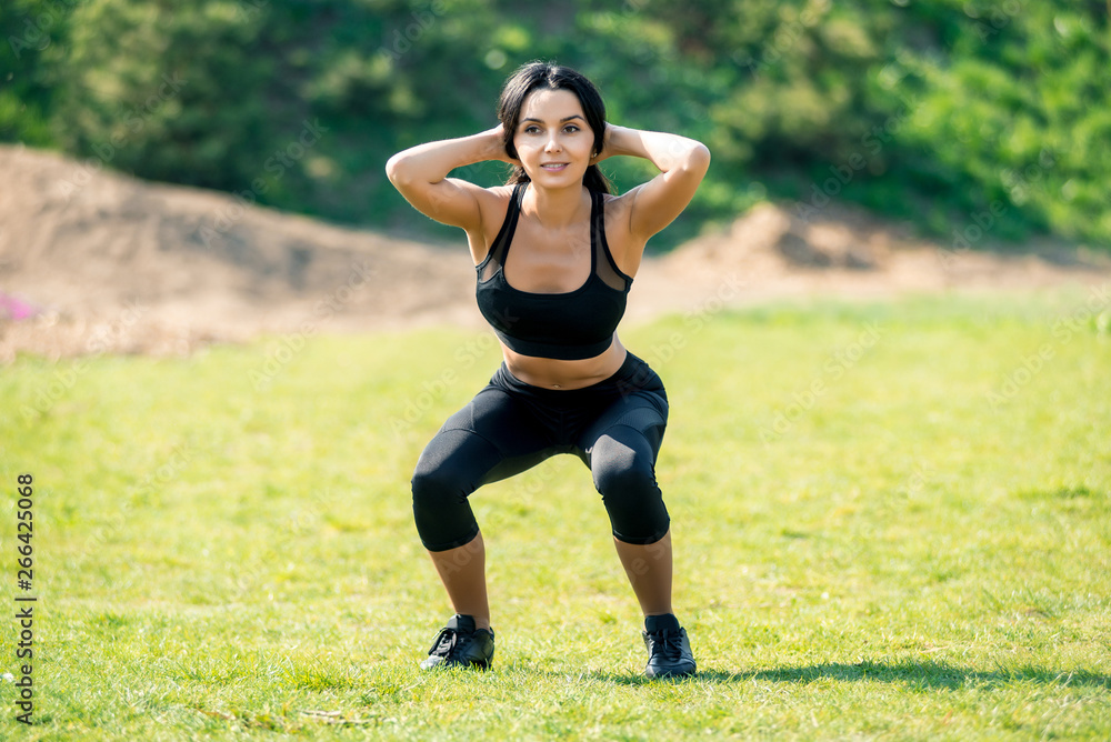 Slender beautiful girl with dark hair in a sports uniform crouches in nature, a symbol of healthy lifestyles, strong personality and desire for success and athletic body Slender beautiful girl with dark hair in a sports uniform crouches in nature, a symbol of healthy lifestyles, strong personality and desire for success and athletic body