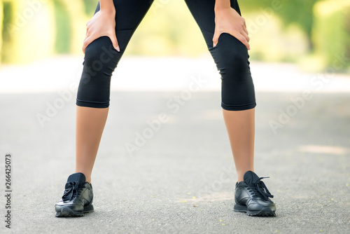 Female legs with close-up hands in them, a symbol of fatigue after running or sports activities