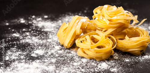 Italian traditional raw pasta on the black stone background