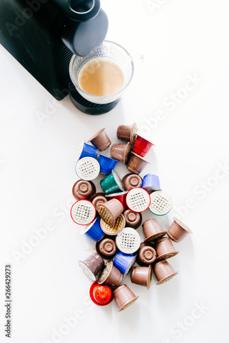 Modern expresso coffee machine , a cup of coffee and Empty Coffee capsules on clean background, top view.