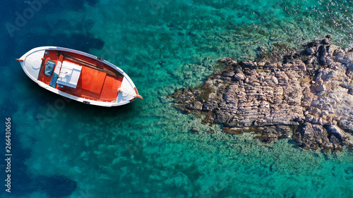 Aerial top view photo of beautiful colourful traditional fishing boat near village of Panormos with turquoise crystal clear sea, island of Tinos , Cyclades, Greece