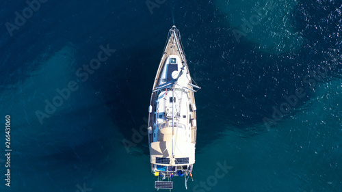 Aerial drone bird's eye top view photo of luxury yacht with wooden deck docked in deep blue waters of Mykonos island, Cyclades, Greece