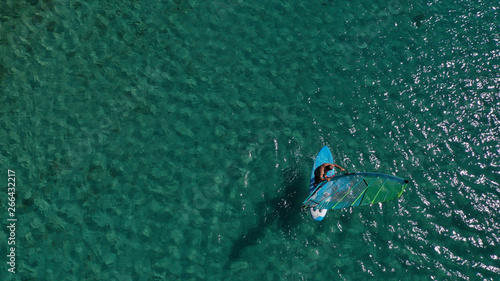 Aerial top view photo of fit man practising wind surfing in exotic open ocean bay with crystal clear emerald sea