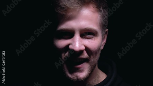 Psychopathic man laughing isolated on dark background, lunatic asylum, madness