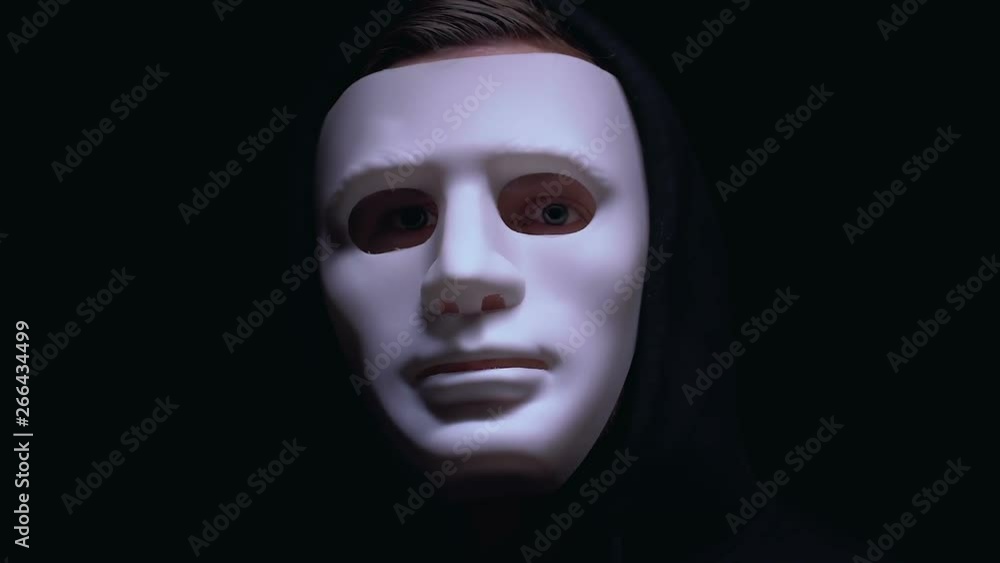 Man hiding wounded face under mask, isolated on black background, criminal Man hiding wounded face under mask, isolated on black background, criminal