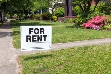 FOR RENT sign posted in lawn advertising home for rent.