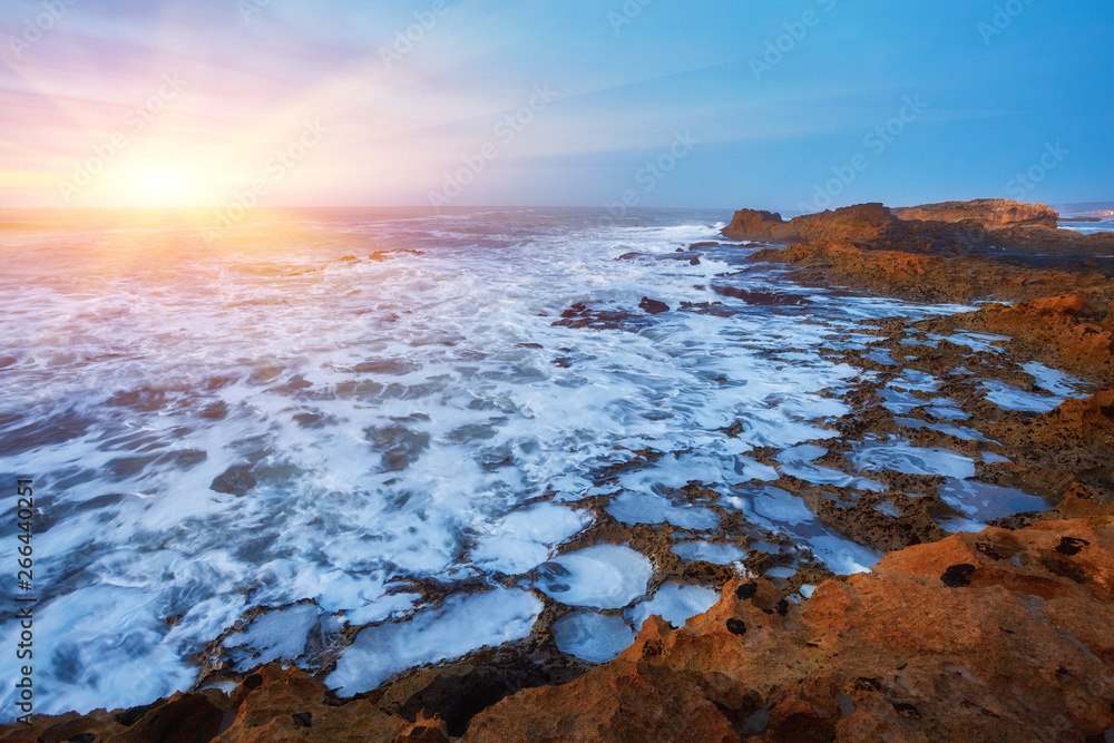 The stony coast of the Atlantic Ocean is washed by the waves during sunset, Essaouira The stony coast of the Atlantic Ocean is washed by the waves during sunset, Essaouira