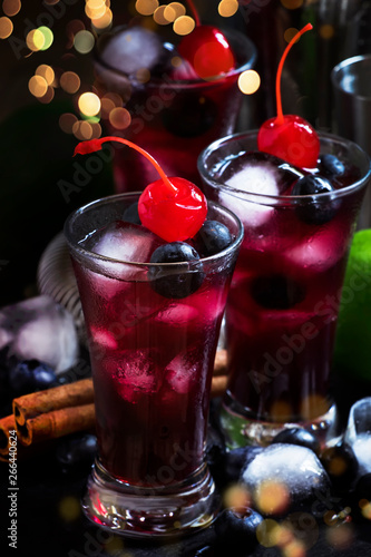 Alcoholic cocktail with blueberry, cinnamon and lime, named berry me, black table, selective focus photo