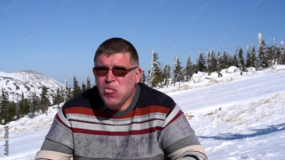 Ski resort man eats Picnic at the ski resort in winter in Sunny weather close-up A man eats a hamburger at a ski resort in winter in warm weather on the background of snowy mountains and blue sky Ski resort man eats Picnic at the ski resort in winter in Sunny weather close-up A man eats a hamburger at a ski resort in winter in warm weather on the background of snowy mountains and blue sky