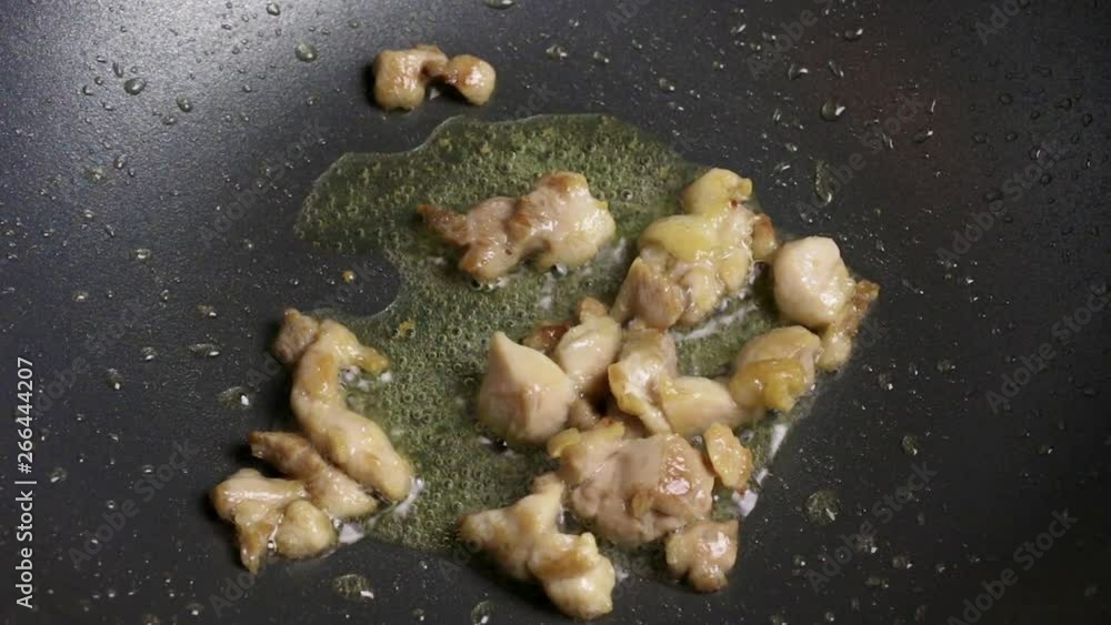 Chopped chicken fillet slices are fried in bioling oil in a wok pan. Part of the process of cooking on the homemade recipe Close. Chopped chicken fillet slices are fried in bioling oil in a wok pan. Part of the process of cooking on the homemade recipe Close.