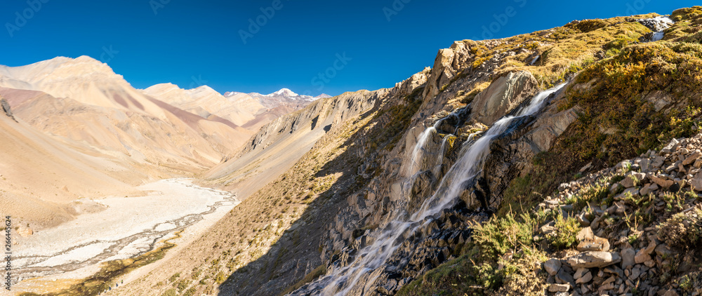 Water stream starts to melt from the summits snow and flows along it steep slopes making amazing waterfalls inside central Andes mountains. Amazing view of the huge rugged terrain Andes valleys scenic