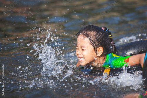 Fototapeta Naklejka Na Ścianę i Meble -  Cute asian  child girls playing water with inflatable ring in the river in summer time with fun and happiness