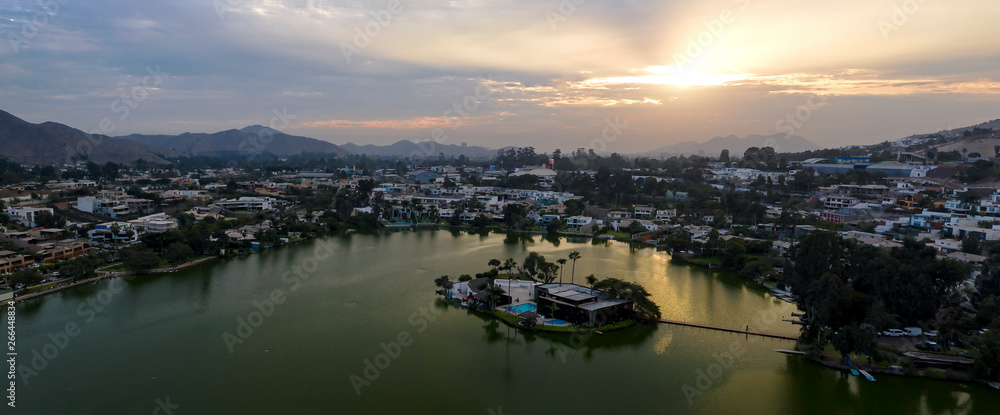 Lima, Perú - May 4 2019:  Panoramic aerial view of Las Lagunas in La Planicie. Lake at sunset with houses of high class.