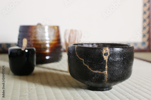Kintsugi : Repair of crack pottery tea cup on tamami blur background