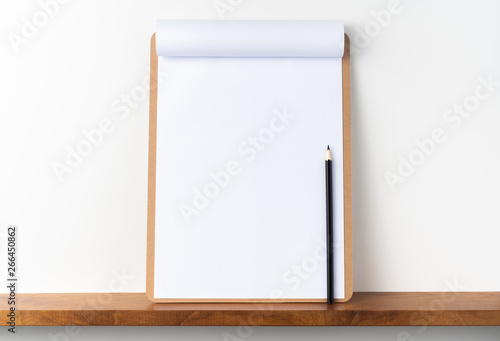 white flipped paper on clipboard on bookshelf © voyata