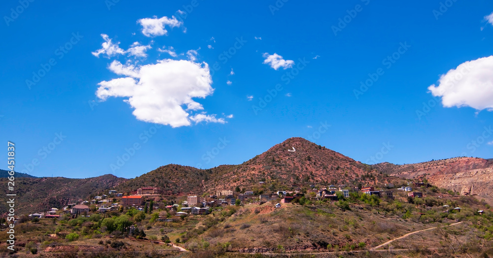 Jerome, Arizona, USA seen in the distance under bright blue skies with white clouds
