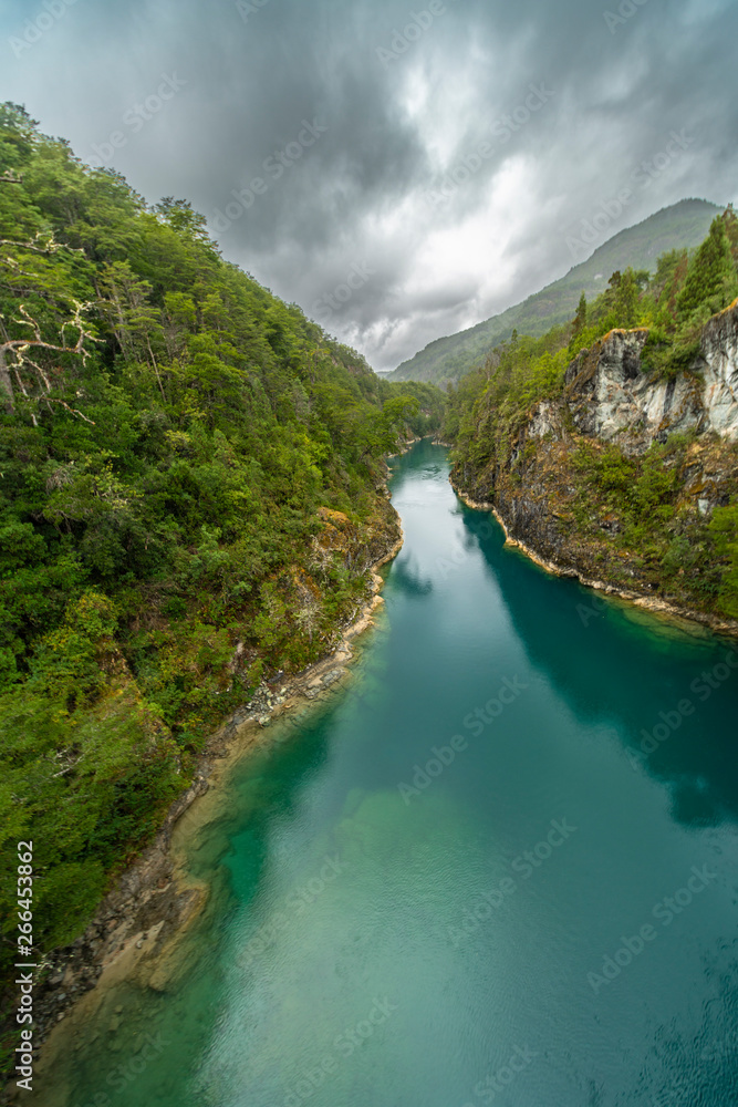 An amazing landscape at north Chilean Patagonia, Puelo river moves around the narrow gorge with its turquoise waters on an awe idyllic natural environment outdoor rugged landscape under a dramatic sky