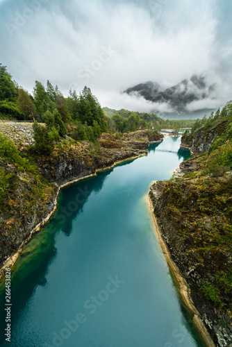 Awe hanging bridge at north Chilean Patagonia, Puelo river moves around the narrow gorge with its turquoise waters on an awe idyllic natural environment outdoor rugged landscape under a dramatic sky
