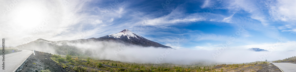 Amazing panoramic view of Osorno Volcano volcanic cone summit. Awe volcanic scenery on a remote location on a misty day with a moody atmosphere and the sun creating halos because of frozen particles
