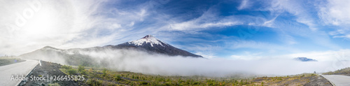 Amazing panoramic view of Osorno Volcano volcanic cone summit. Awe volcanic scenery on a remote location on a misty day with a moody atmosphere and the sun creating halos because of frozen particles