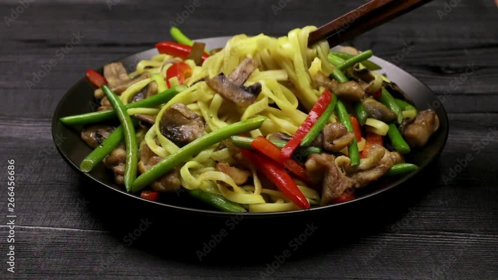Stir fryed noodls with garlic sprouts and chopped pieces of mushrooms with chicken sautéed in an oil in a wok pan. Cooking with champignons and fried noodles according to homemade recipe. Close. Stir fryed noodls with garlic sprouts and chopped pieces of mushrooms with chicken sautéed in an oil in a wok pan. Cooking with champignons and fried noodles according to homemade recipe. Close.